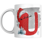 Christmas mug with red letter U wearing Santa hat, snowy trees, snowman, and sleigh silhouette. Perfect holiday mug for festive coffee or gifting.