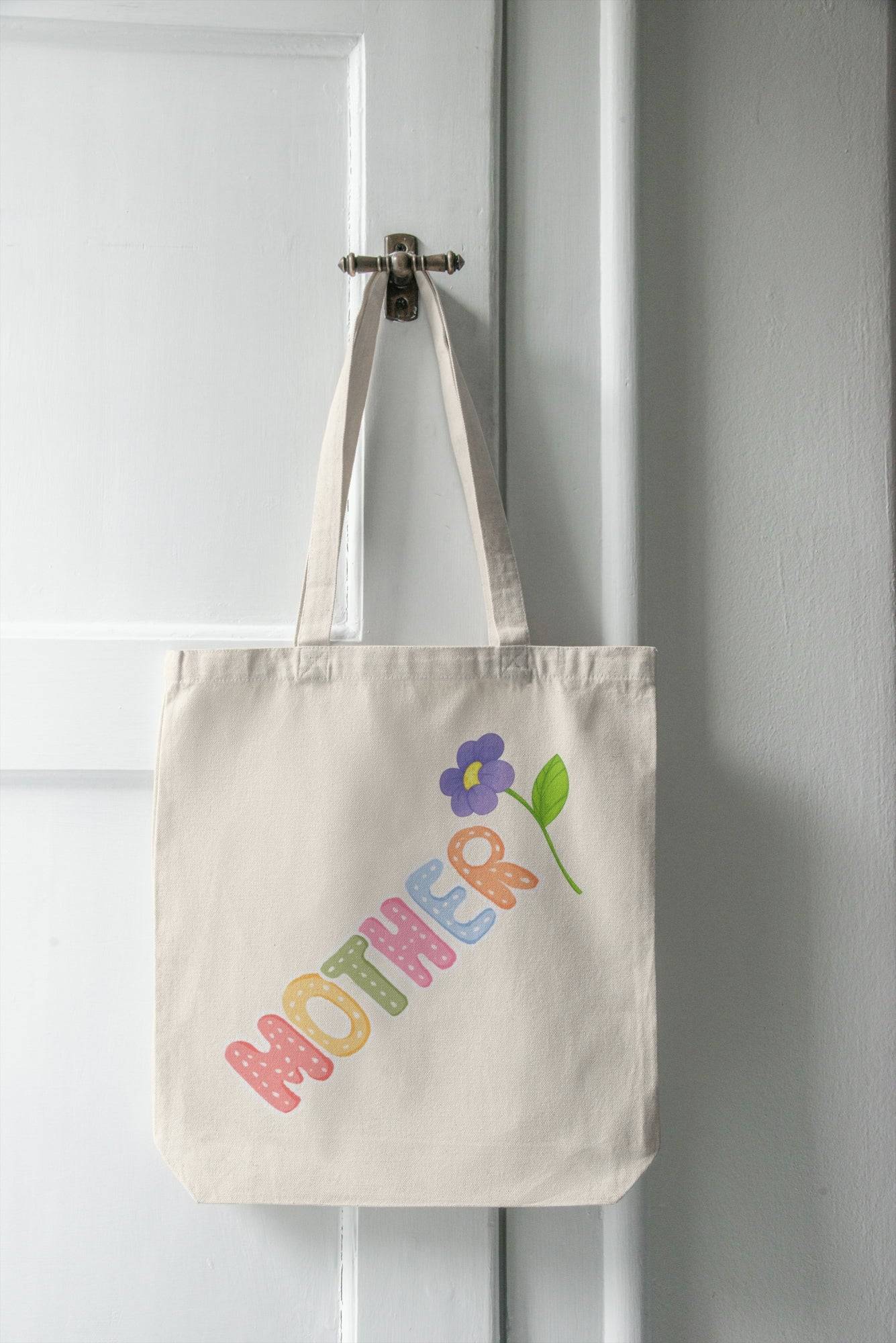 Colorful Mother tote bag with flower design hanging on white door. Ideal gift for moms, perfect for carrying daily essentials in style.